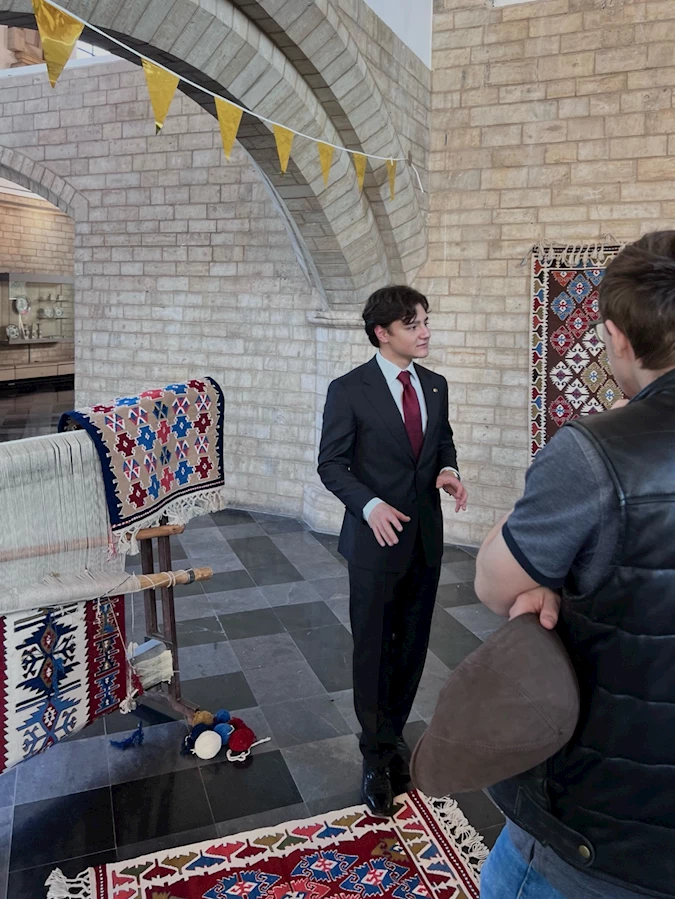 A person in a suit talking to another person

Description automatically generated