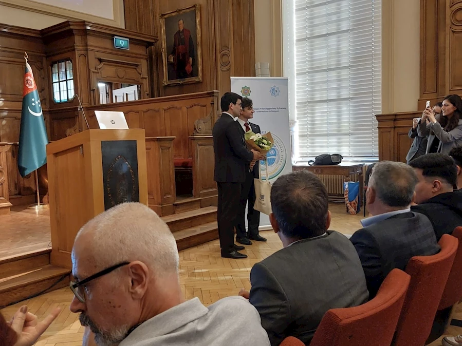 A person standing in front of a podium with a person holding a bouquet of flowers

Description automatically generated