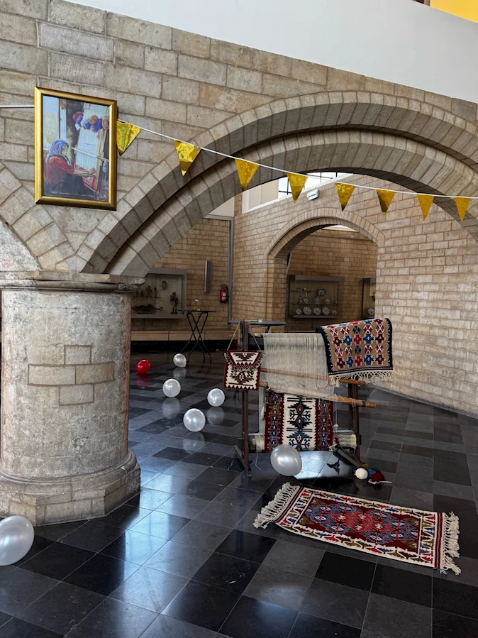 A room with a brick wall and a rug and balloons

Description automatically generated